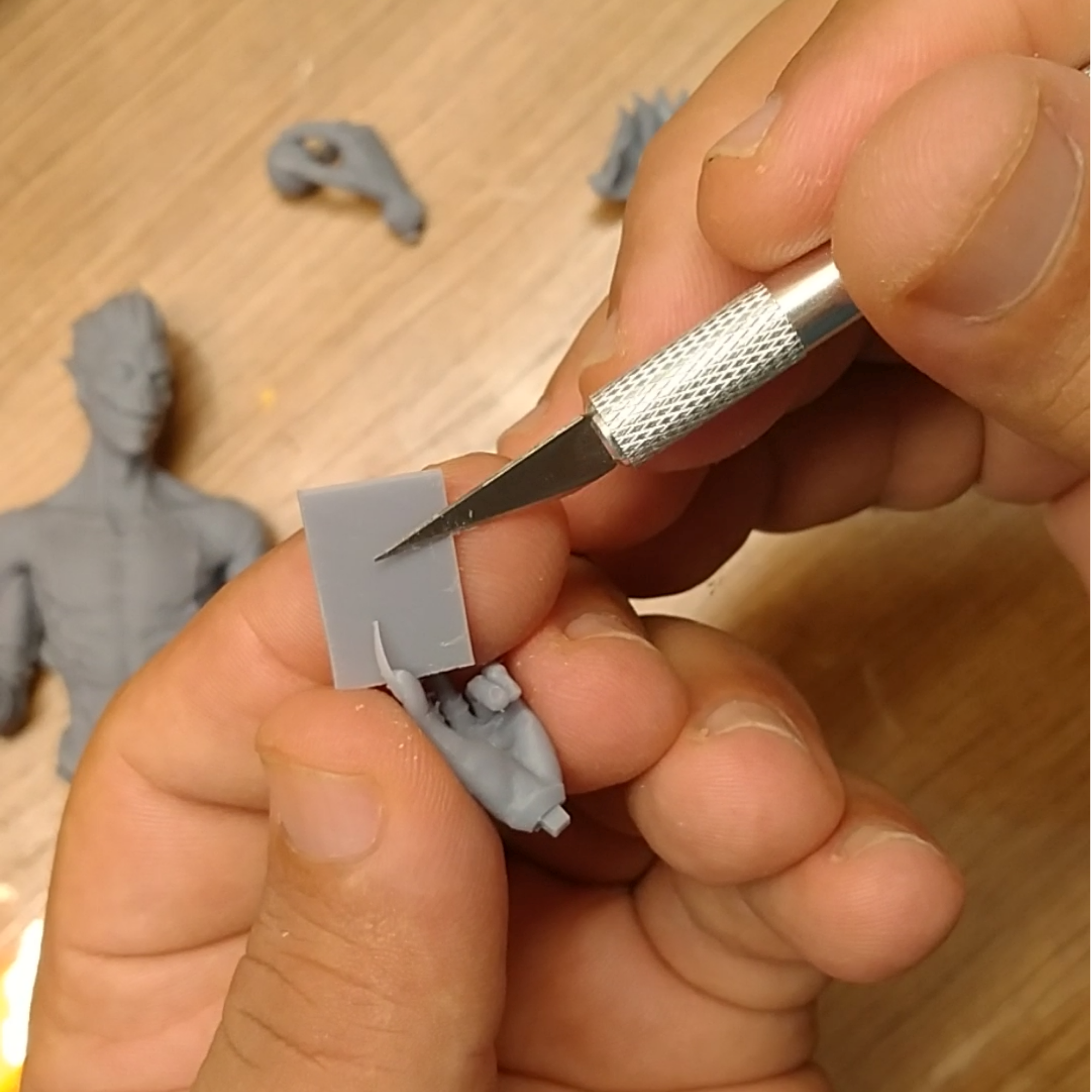 Removing supports from a resin 3D printed figure part with a precision knife.