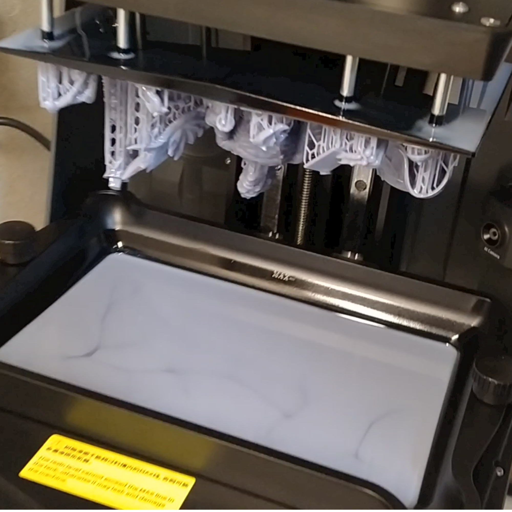 Resin 3D printer build plate with freshly printed model parts and supports.