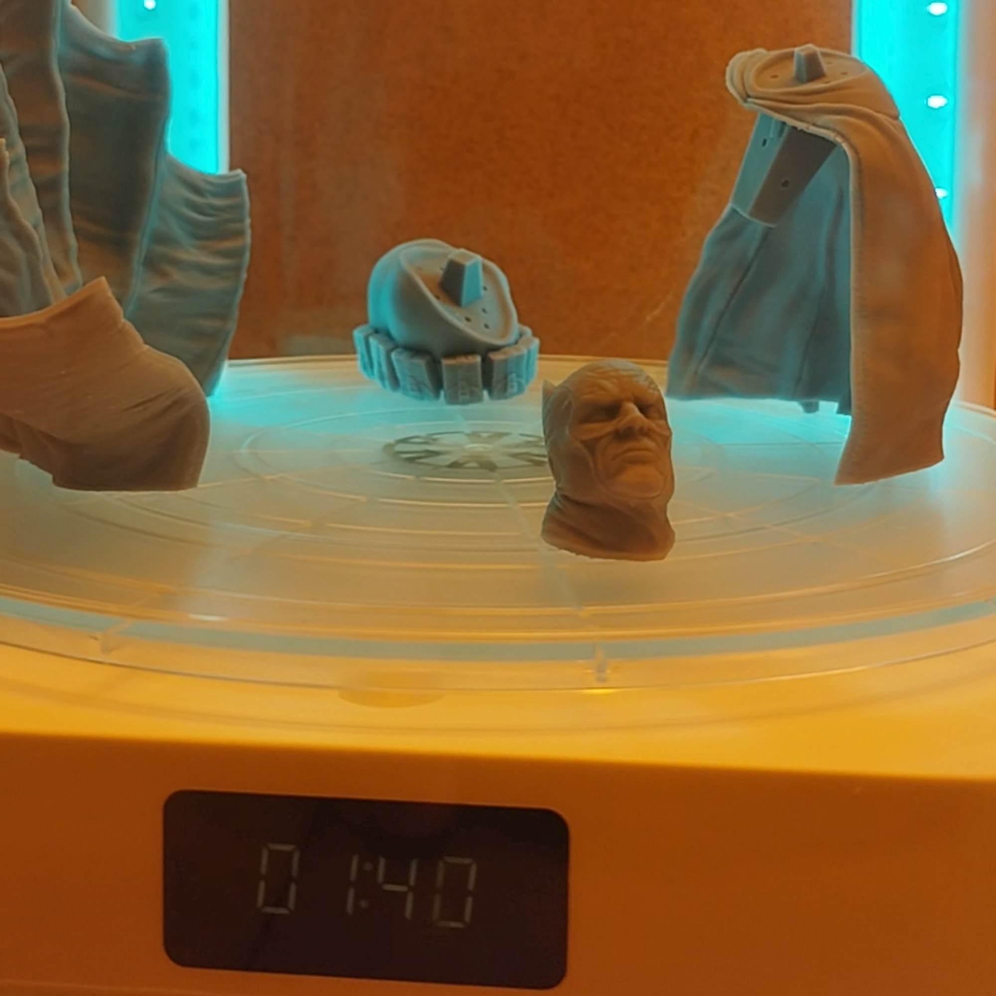 Resin 3D printed figure parts curing inside a UV curing station.
